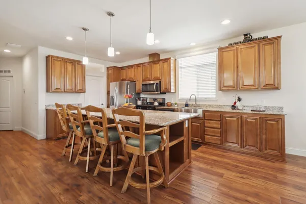 a kitchen with stainless steel appliances granite countertop a stove a sink dishwasher a dining table and chairs with wooden floor