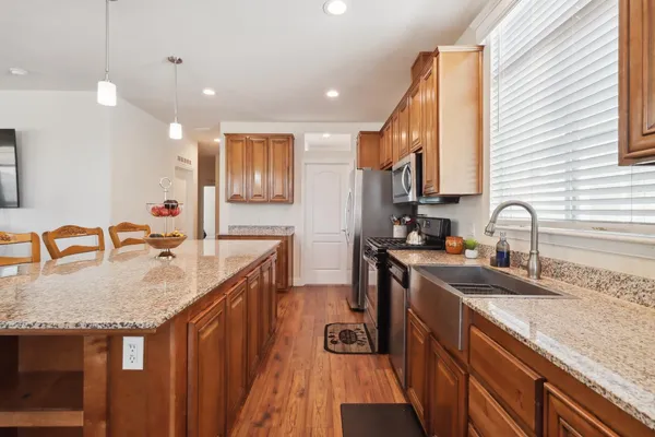 a kitchen with stainless steel appliances granite countertop a sink a stove and a wooden cabinets