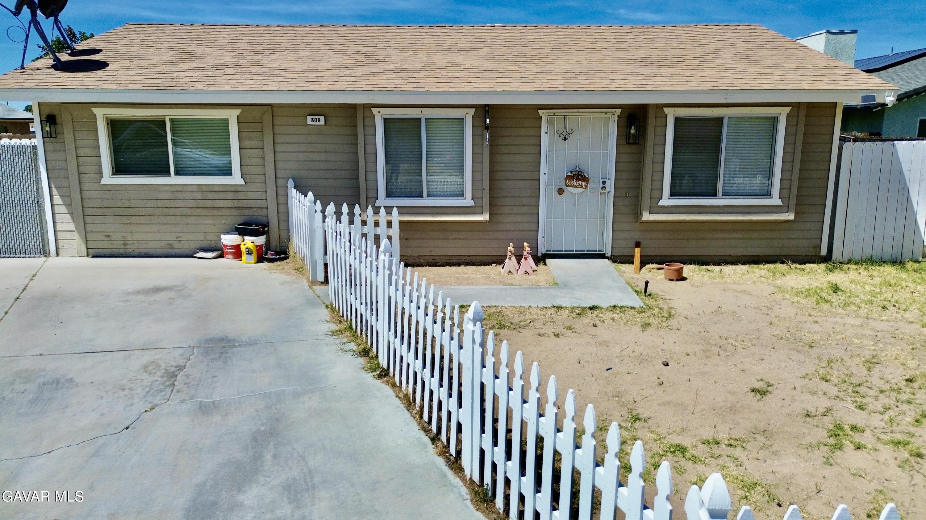 a view of a house with wooden fence next to a yard