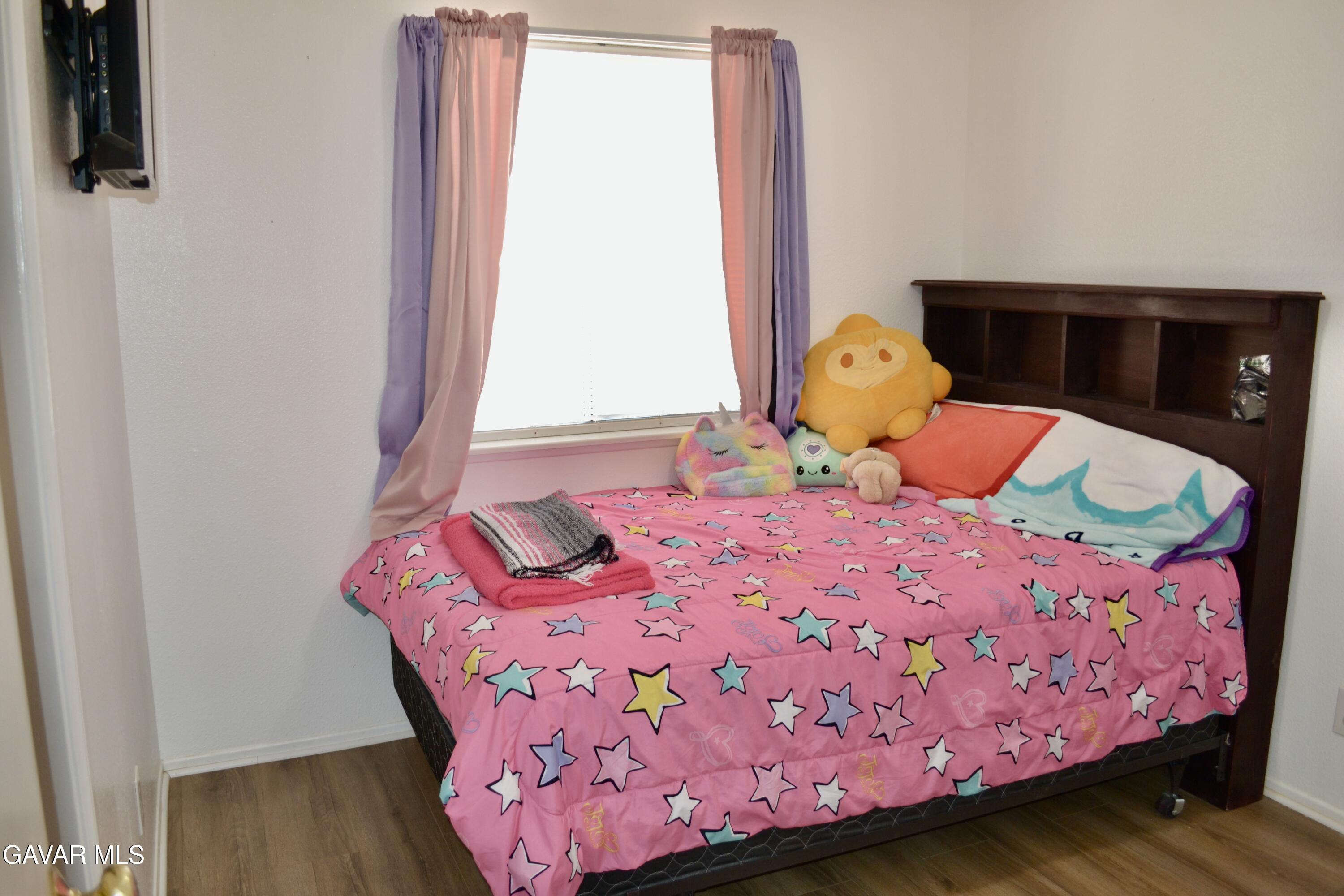 809 South Sunset Street Ridgecrest, CA 93555 - Photo 9 of 21 a bedroom with a bed and wooden floor