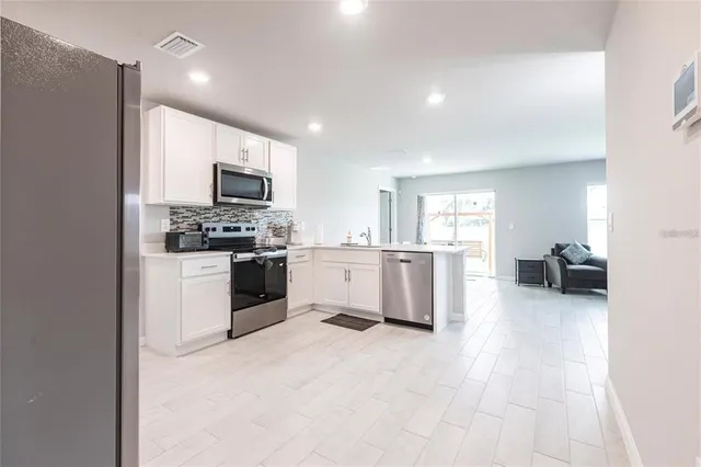 a large white kitchen with a stove a sink dishwasher and a refrigerator with wooden floor