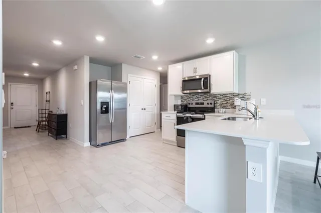 a kitchen with stainless steel appliances a refrigerator sink and white cabinets