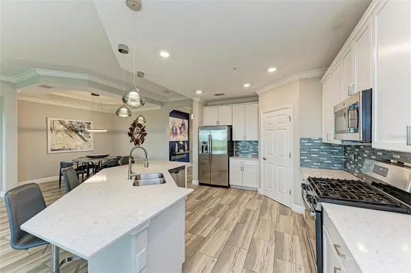 a large kitchen with a counter space a sink stainless steel appliances and cabinets