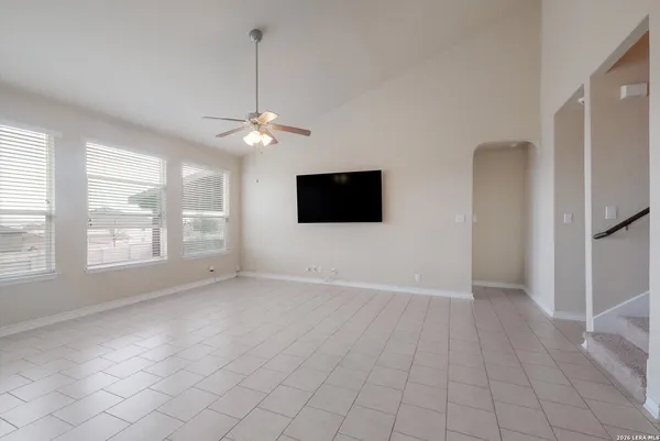 an empty room with windows and ceiling fan