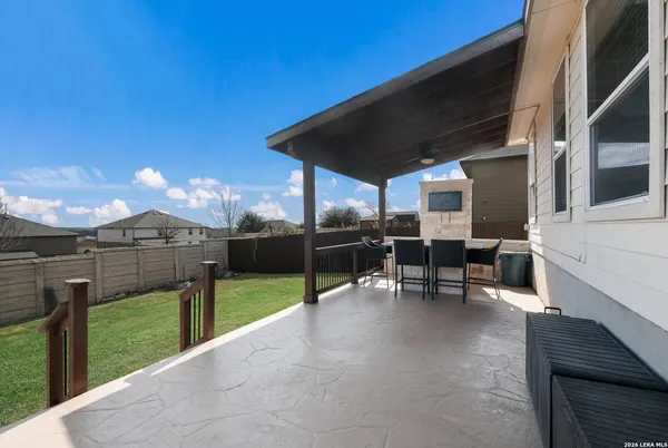 a view of a patio with a table and chairs under an umbrella with a small yard