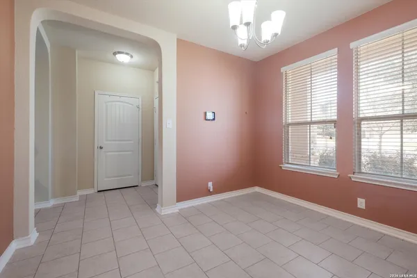 a view of an empty room with window and chandelier fan