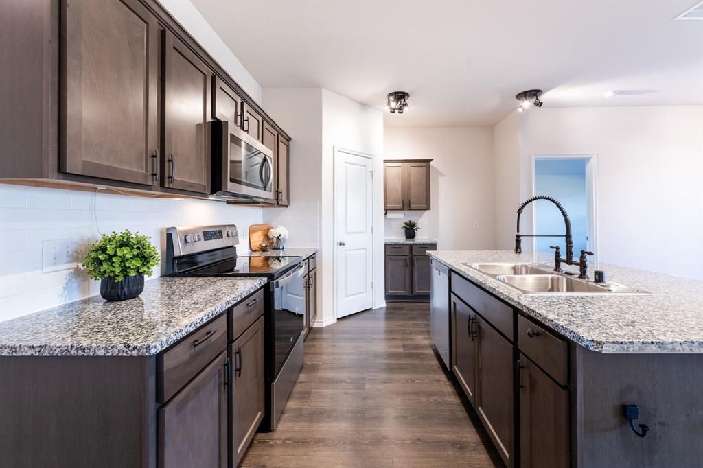 2101 Brisbon Street Fate, TX 75189 - Photo 8 of 39 a kitchen with stainless steel appliances granite countertop a sink a stove top oven a counter space and cabinets