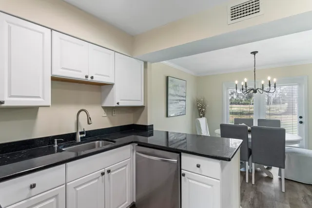 a kitchen with granite countertop a sink cabinets and wooden floor