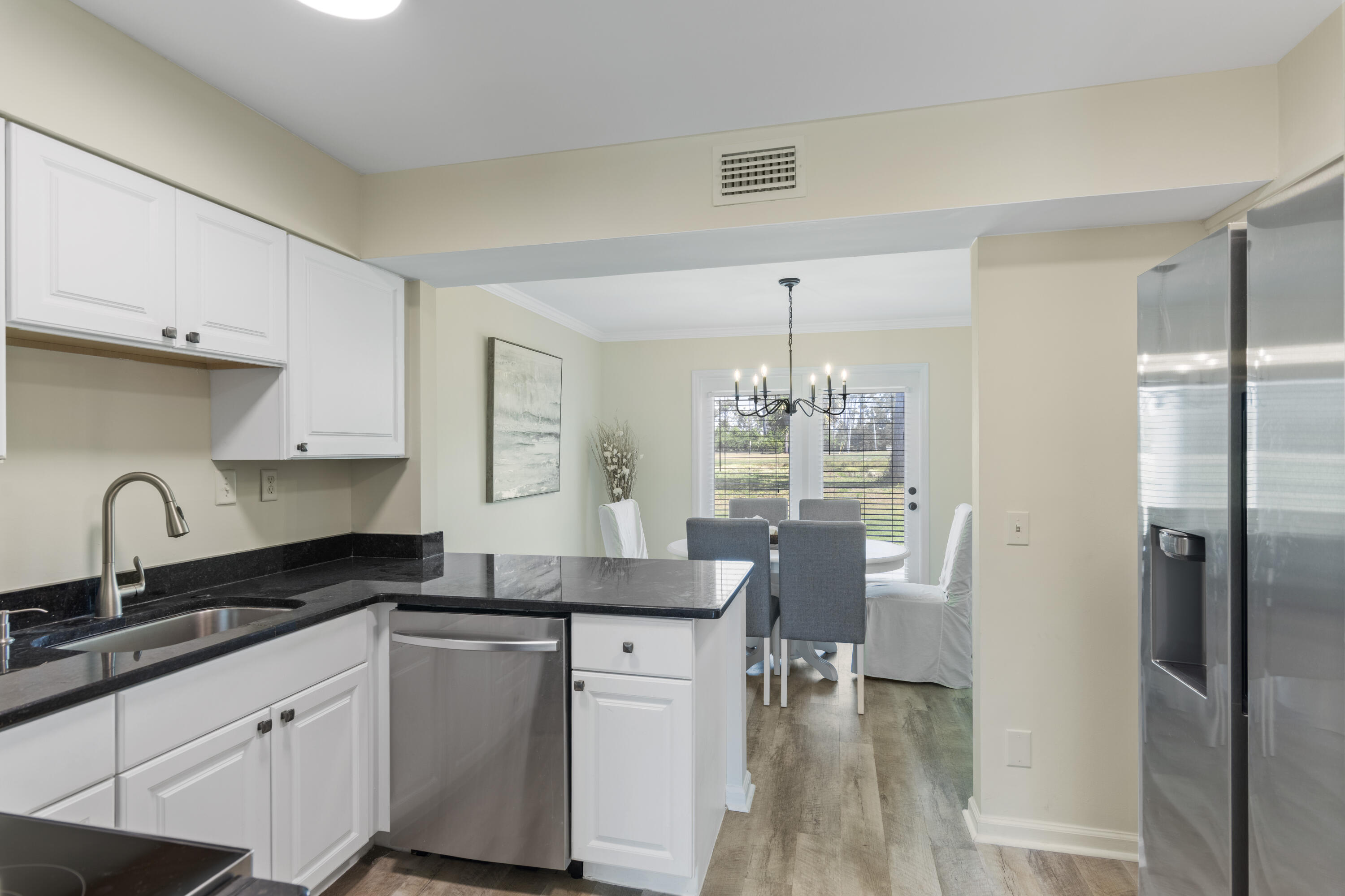 4300 Bay Point Road, Unit 402 Panama City Beach, FL 32408 - Photo 12 of 34 a kitchen with stainless steel appliances granite countertop a refrigerator a sink dishwasher a stove and a dining table with wooden floor
