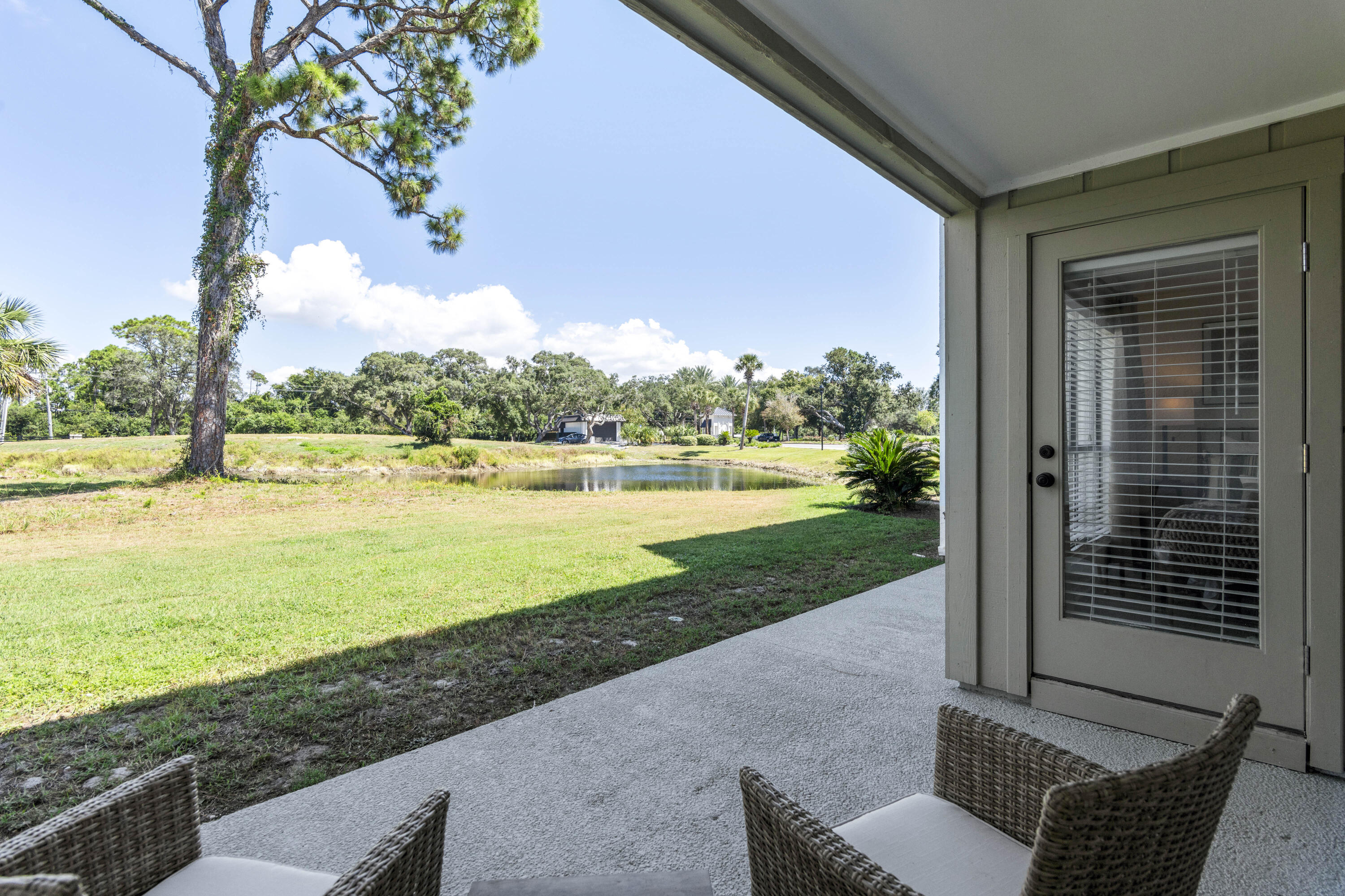 4300 Bay Point Road, Unit 402 Panama City Beach, FL 32408 - Photo 33 of 34 a view of a patio with lawn chairs floor to ceiling window and yard