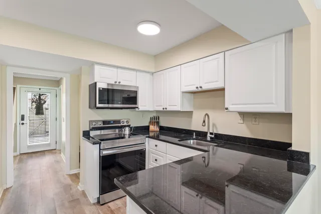 a kitchen with granite countertop a stove a sink and a microwave