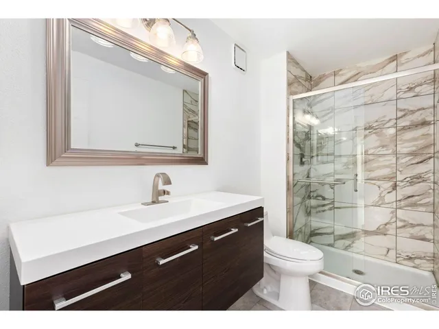a bathroom with a sink a toilet a mirror and shower