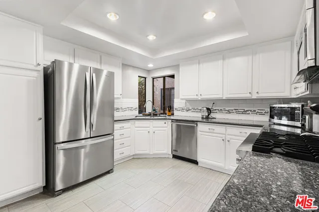 a kitchen with granite countertop a refrigerator stove top oven and sink