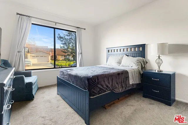 a bedroom with a bed lamp and a large window