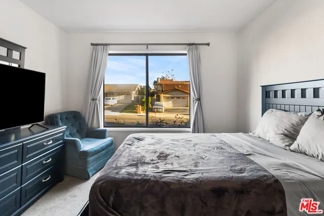 a bedroom with a bed and a flat tv screen on dresser