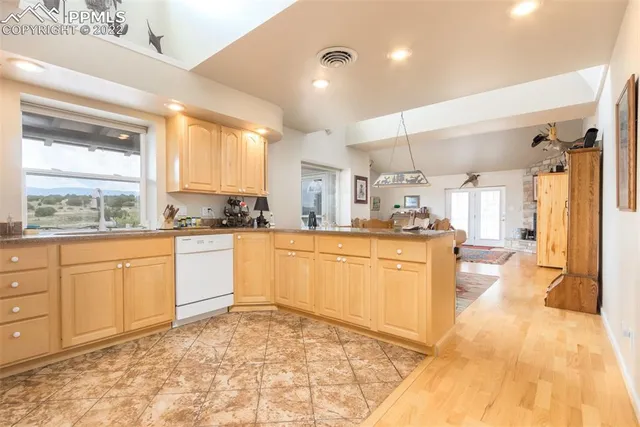 a large kitchen with kitchen island a stove a sink dishwasher and white cabinets with wooden floor