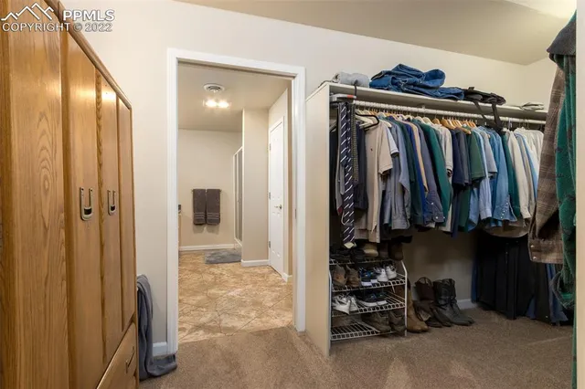 a view of walk in closet with clothes and shoes