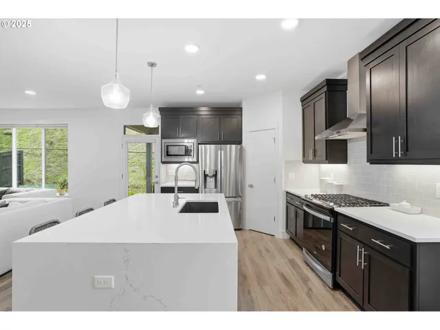 a kitchen with stainless steel appliances a sink stove and wooden floor