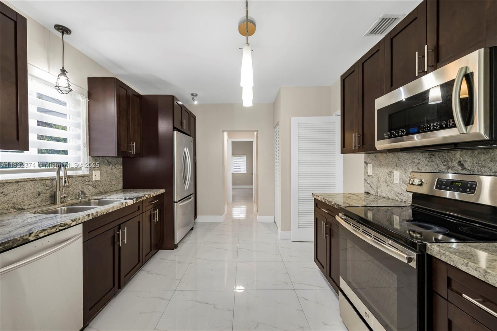 340 Southwest 25th Road Miami, FL 33129 - Photo 13 of 42 a kitchen with stainless steel appliances granite countertop a sink stove and refrigerator