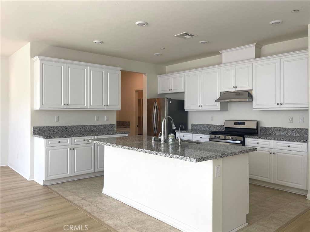 2076 East Bulletin Privado Ontario, CA 91764 - Photo 5 of 20 a kitchen with kitchen island granite countertop a sink a counter top space and cabinets