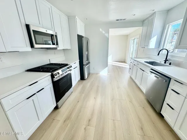 a kitchen with granite countertop a sink dishwasher stove and microwave with wooden floor