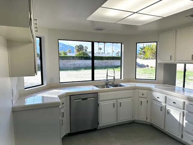 a kitchen with sink attached with white cabinets