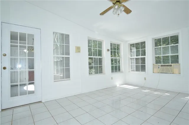 a view of an empty room with a window and kitchen view