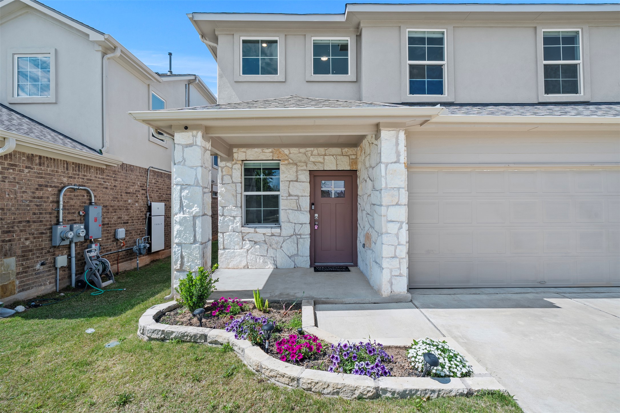 120 Ellinger Road Georgetown, TX 78626 - Photo 4 of 28 Contemporary facade featuring a stone veneer front porch with square columns, a dark panel front door with window accents, and a wide driveway leading to a two-car garage