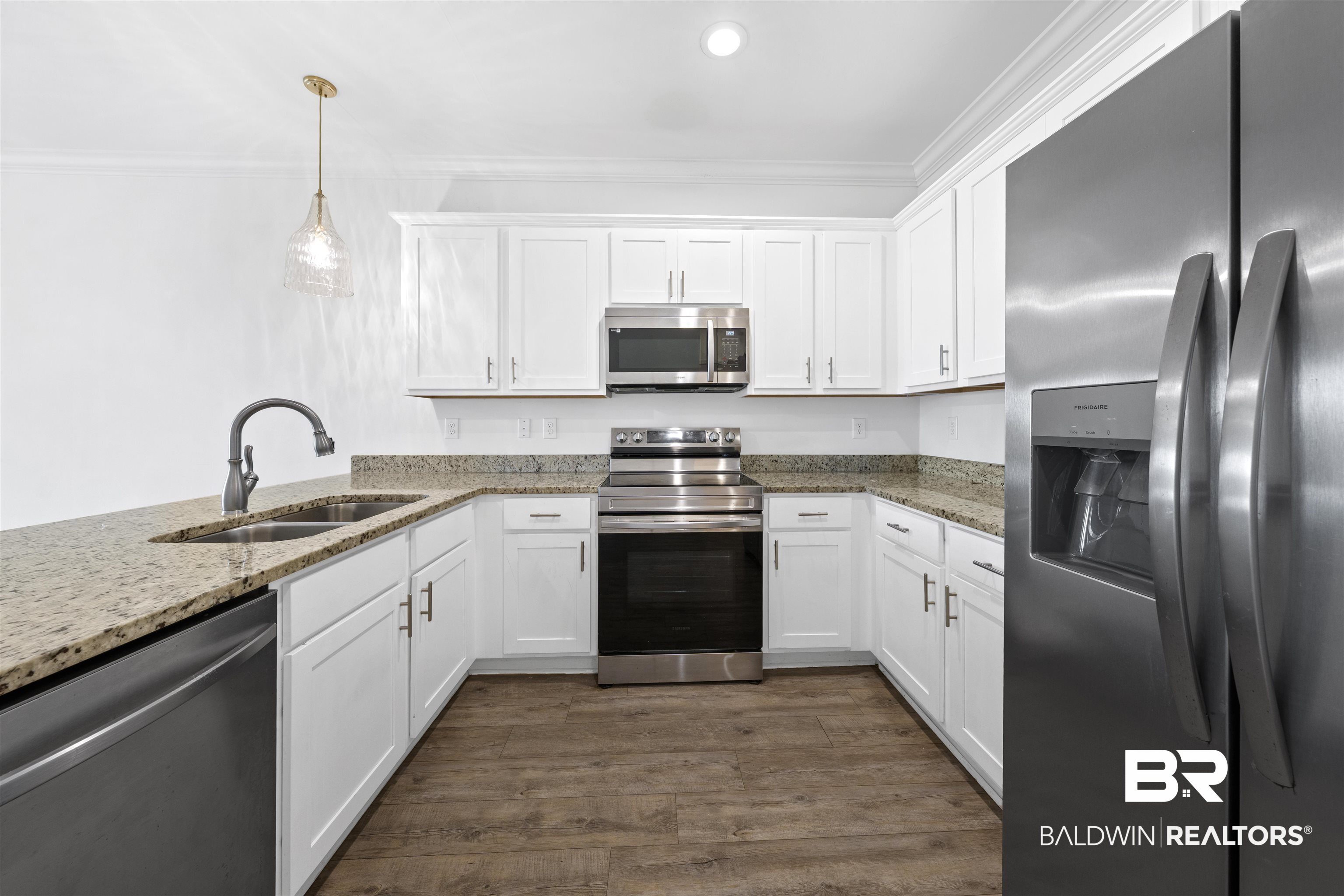 2651 South Juniper Street, Unit 1801 Foley, AL 36535 - Photo 7 of 16 U-shaped kitchen featuring white cabinetry with brushed nickel hardware, light-toned granite countertops, and stainless steel appliances including a built-in microwave, range, and refrigerator with external dispenser