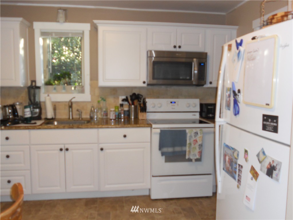 705 North 88th Street Seattle, WA 98103 - Photo 12 of 22 a kitchen with white cabinets and white appliances