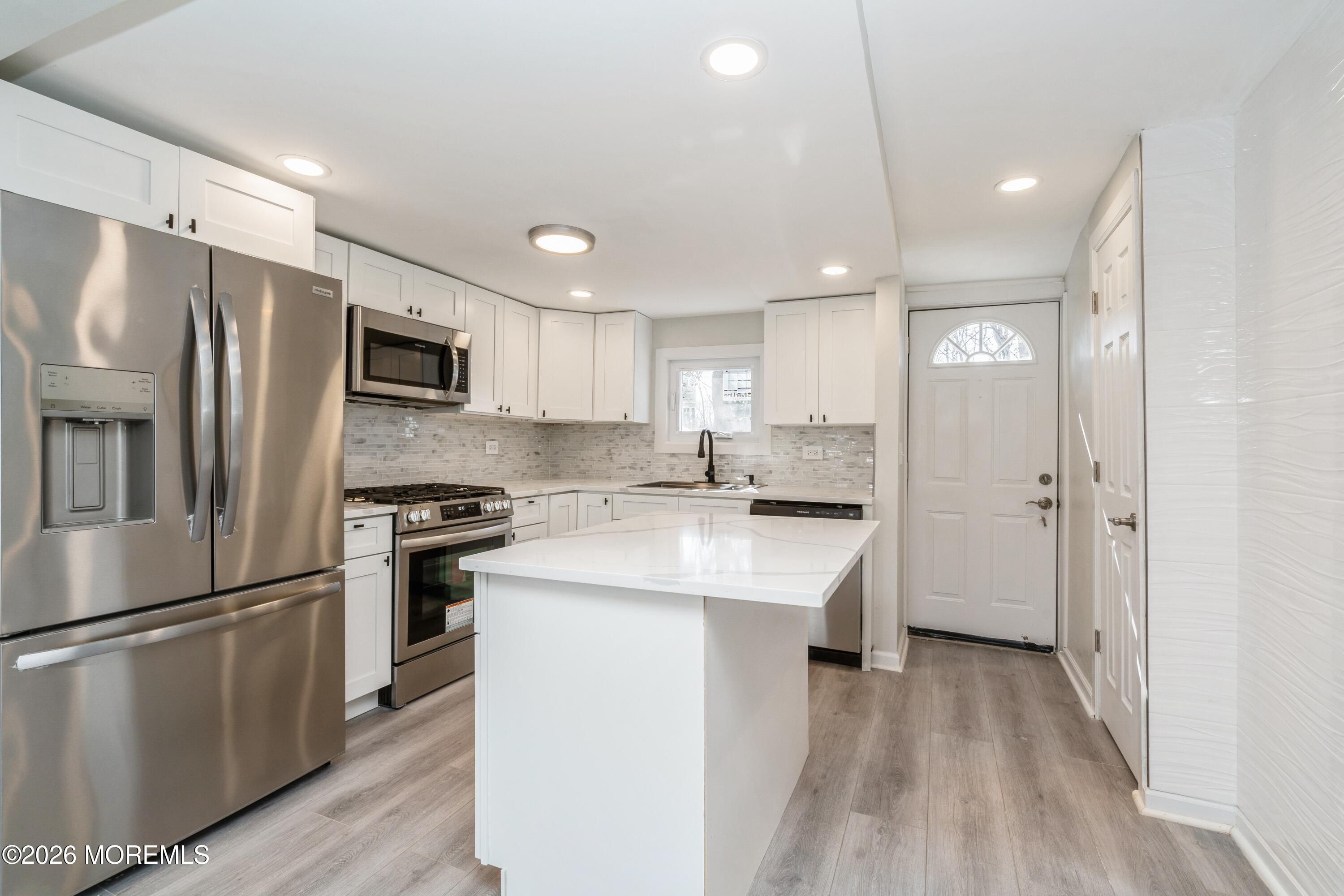 21 Mathiasen Place, Unit A Matawan, NJ 07747 - Photo 5 of 12 a kitchen with stainless steel appliances a refrigerator stove microwave and cabinets