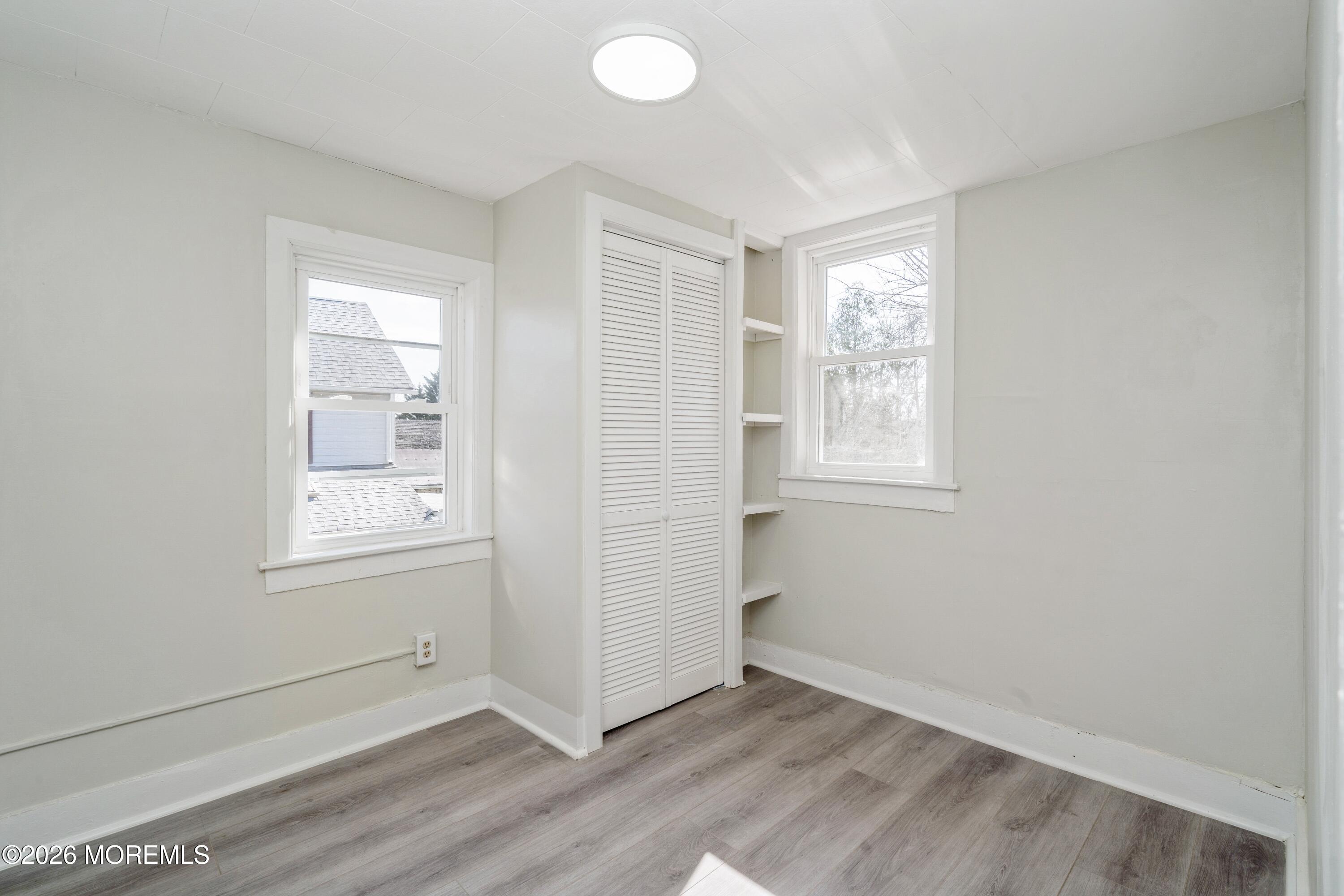 21 Mathiasen Place, Unit A Matawan, NJ 07747 - Photo 8 of 12 an empty room with wooden floor and windows