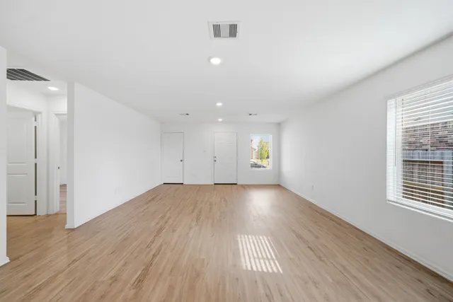 an empty room with wooden floor and windows