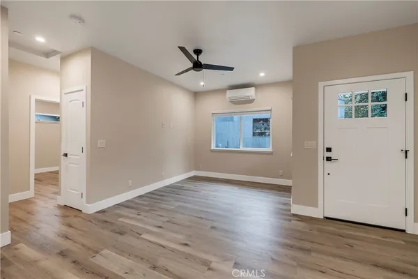 an empty room with wooden floor a ceiling fan and windows