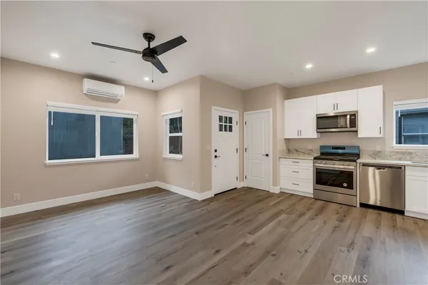 a view of kitchen with sink wooden floor and stainless steel appliances