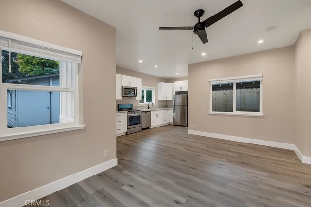 a view of kitchen with stainless steel appliances wooden floor large window and wooden floor