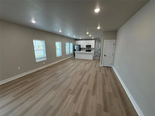 a view of a big room with wooden floor and windows