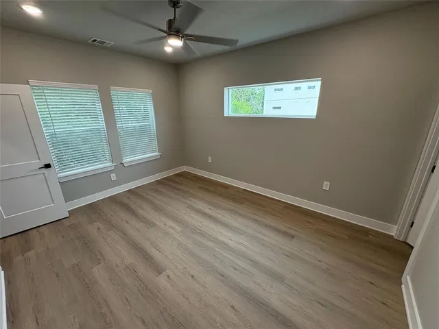 an empty room with wooden floor and windows