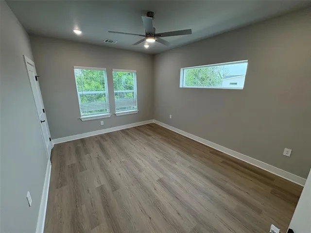 a view of an empty room with a window and a ceiling fan