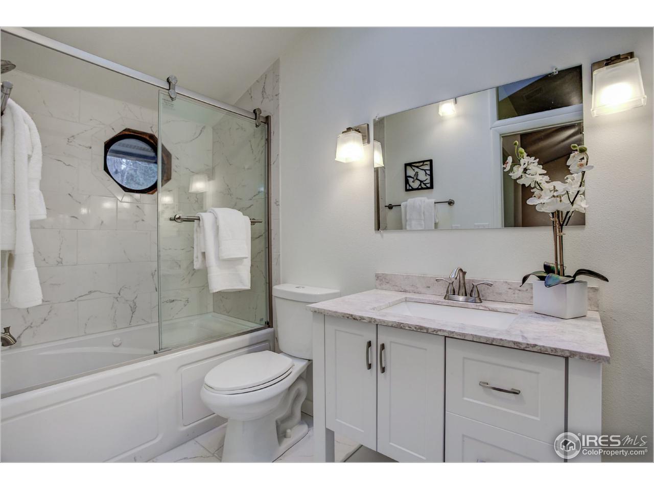 765 Pine Brook Road Boulder, CO 80304 - Photo 25 of 37 a bathroom with a granite countertop sink toilet a mirror a vanity and shower