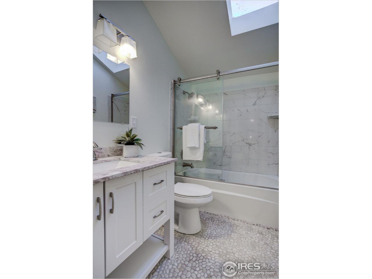 765 Pine Brook Road Boulder, CO 80304 - Photo 31 of 37 a bathroom with a granite countertop toilet a sink and a mirror