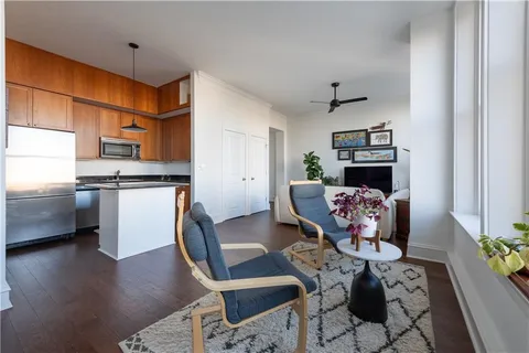 a living room with stainless steel appliances furniture a rug and a kitchen view