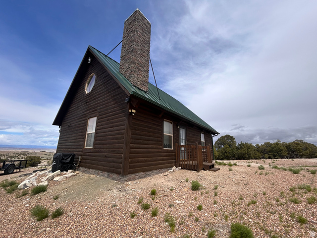 19075 West Honesty Cove Duchesne, UT 84021 - Photo 36 of 44 Log cabin exterior featuring a green metal roof, stone chimney, and wood siding