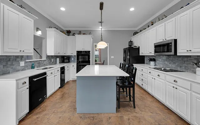 a large kitchen with a stove a sink dishwasher a oven with a dining table and chairs