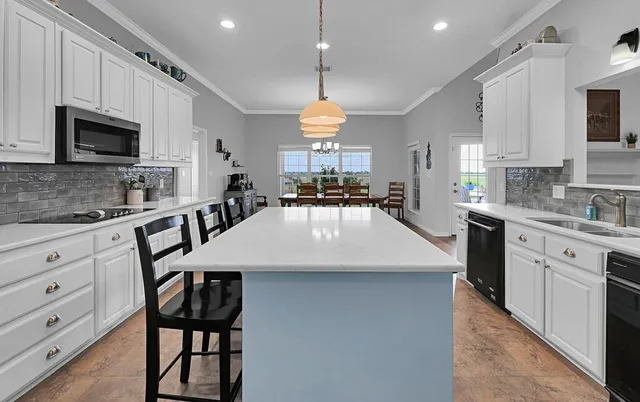 a large kitchen with sink a microwave and cabinets