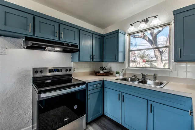 a kitchen with a sink stove top oven and cabinets
