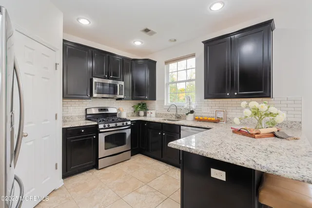 a kitchen with granite countertop wooden cabinets stainless steel appliances and a sink