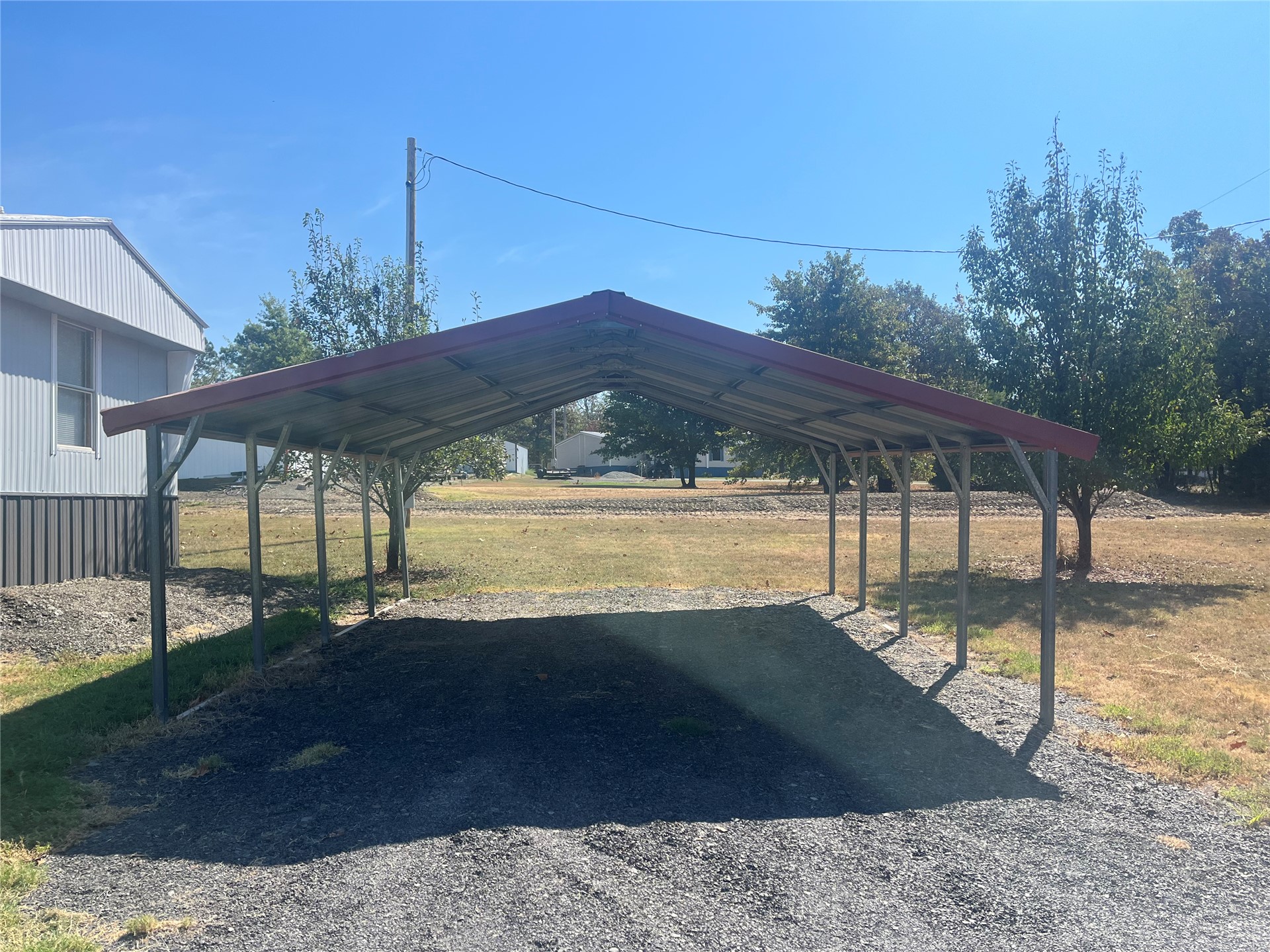 428628 East 1133 Road Porum, OK 74455 - Photo 2 of 16 Metal carport structure with a red roof and gravel flooring