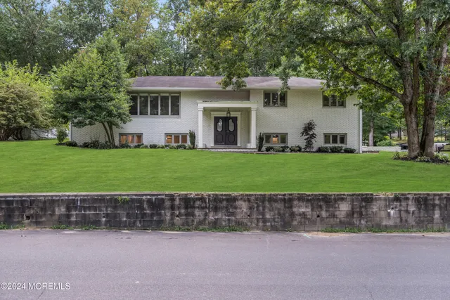 a front view of a house with a garden and a tree