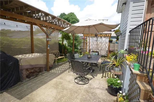 a view of a patio with table and chairs under an umbrella with a small yard
